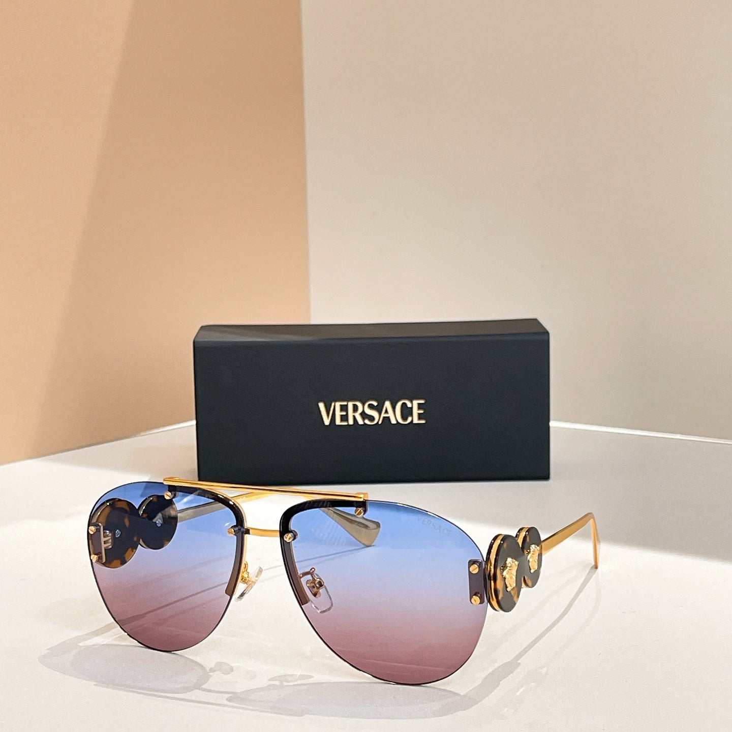 Versace sunglasses with gold frame and tinted purple-brown lenses; logo detail on temples