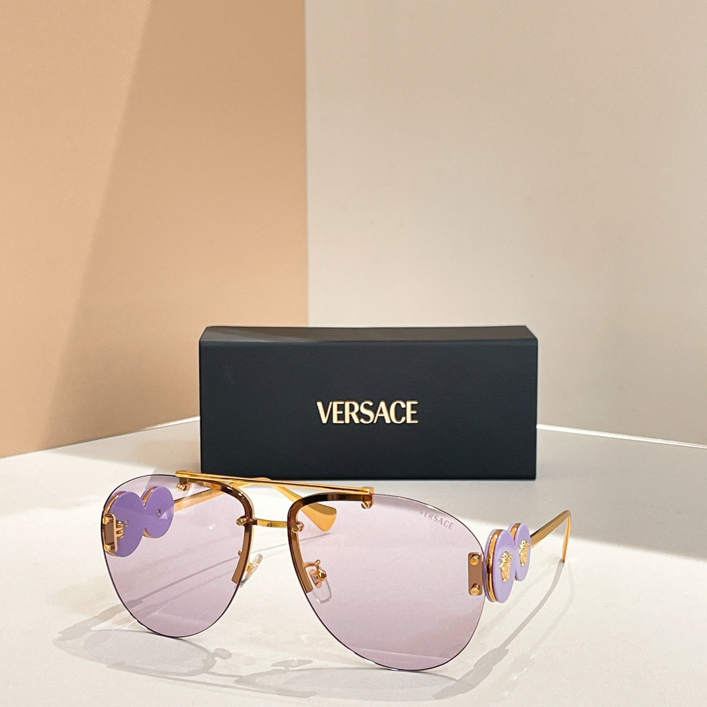 Versace sunglasses with gold frame and light purple lenses; purple logo on temple