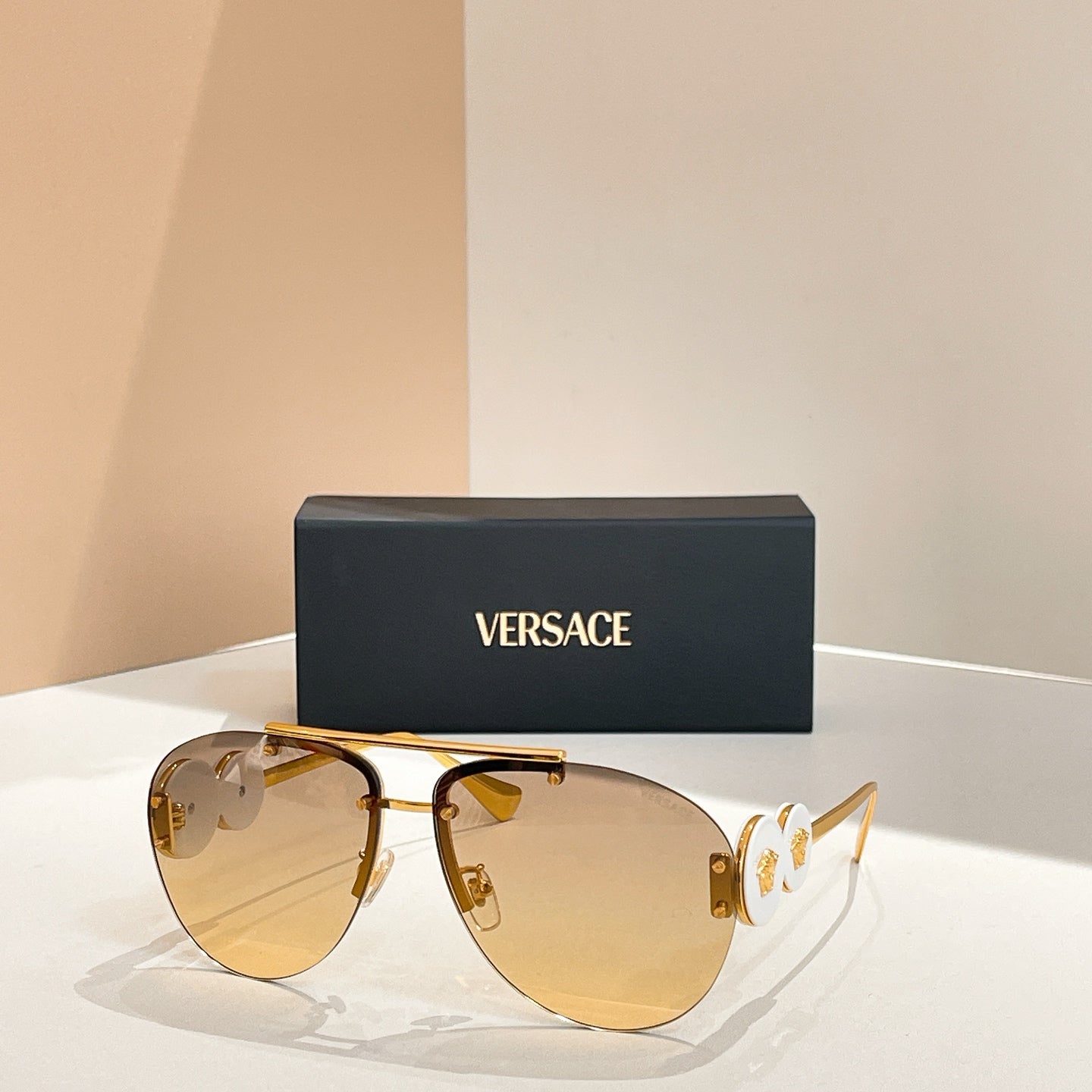 Versace sunglasses with gold frame and golden tinted lenses; logo detail on temple arms