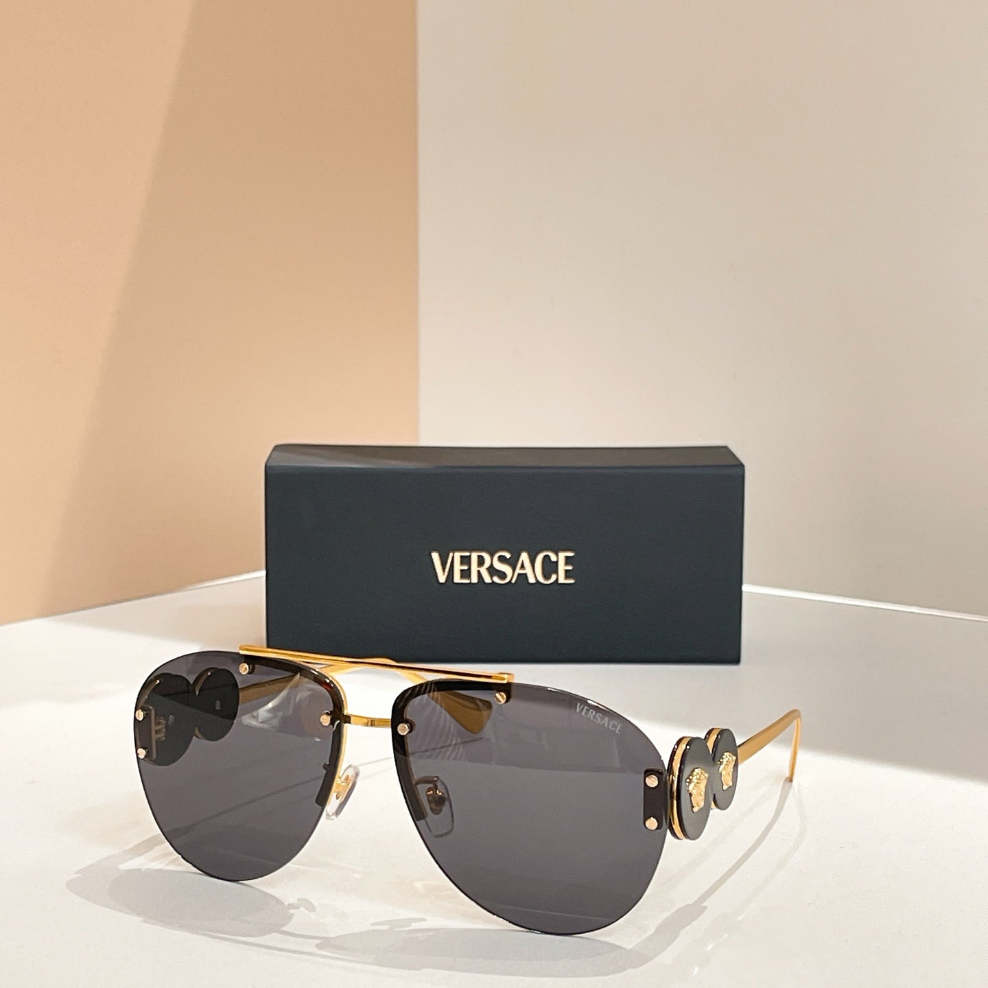 Versace sunglasses with gold frame and dark lenses; logo detail on the temple arms