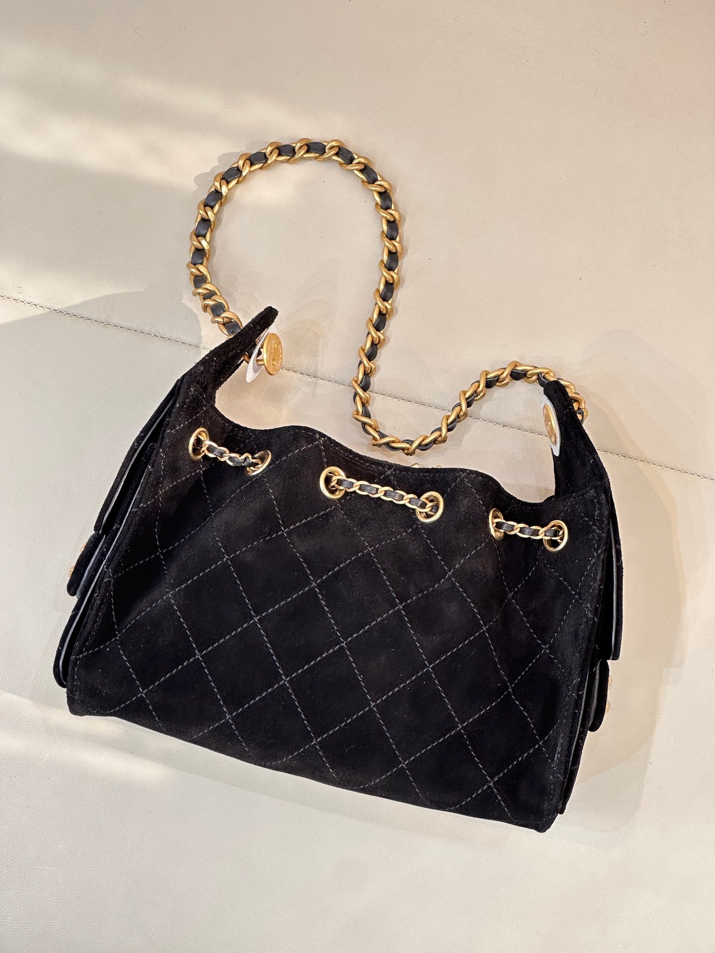 Chanel quilted handbag angled view with gold chain strap and front chain detail, black