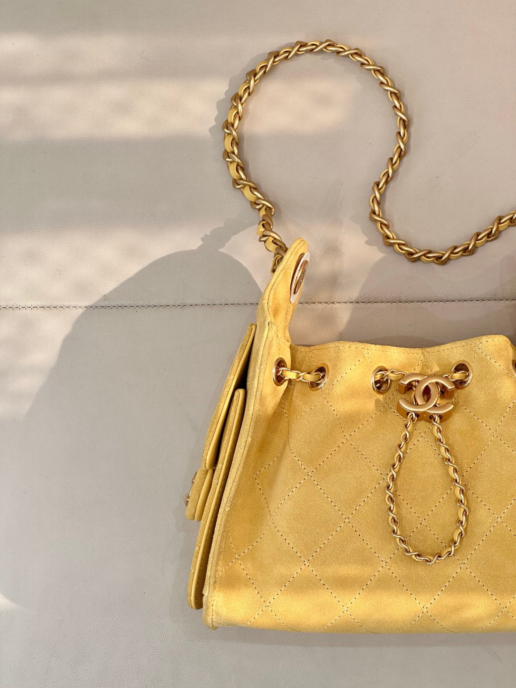 Chanel yellow quilted bucket handbag angled view with gold chain handle