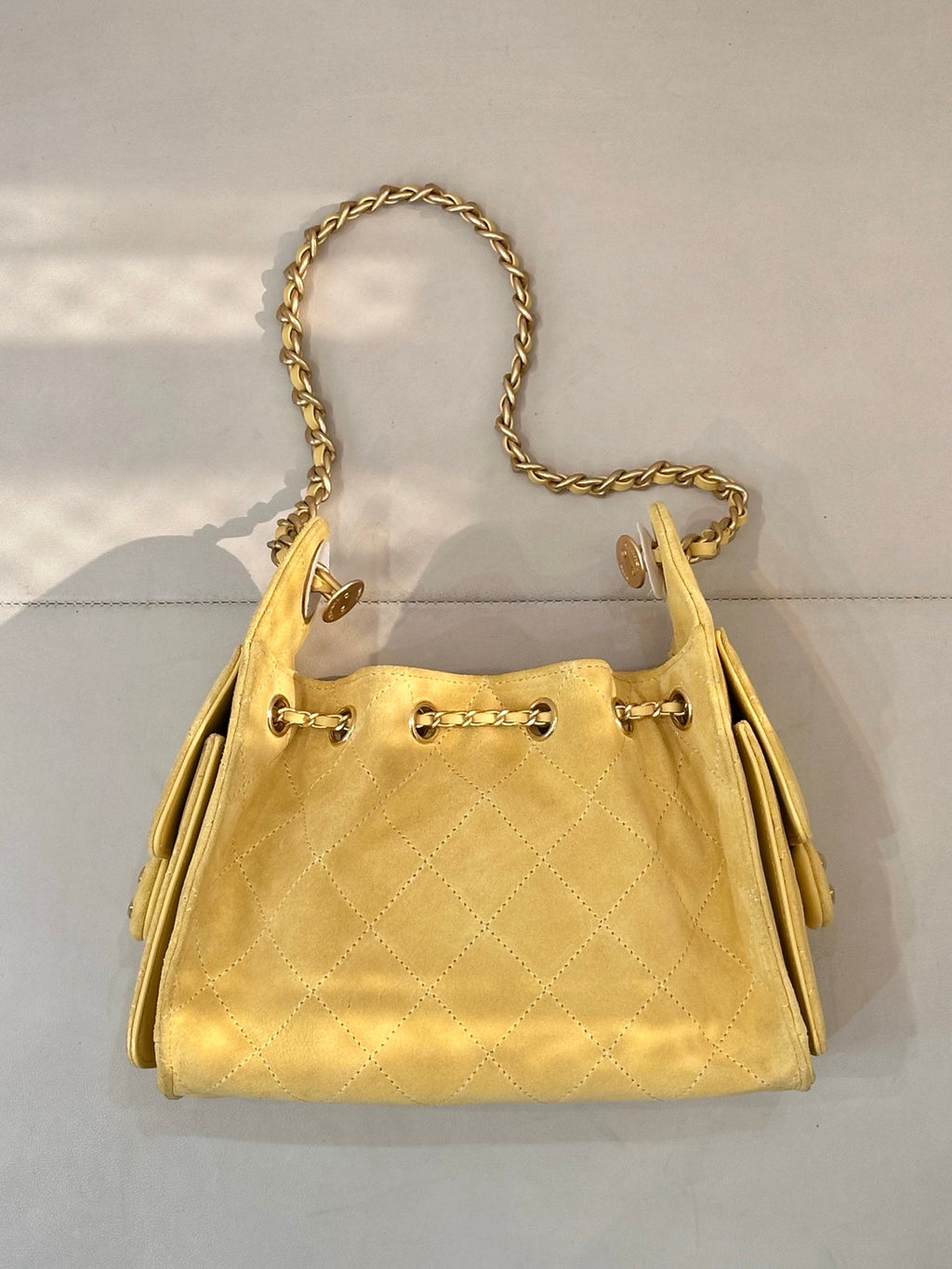 Chanel yellow quilted bucket handbag front view with gold chain handle