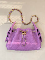 Purple quilted Chanel handbag with chain strap, top handles, and gold CC clasp