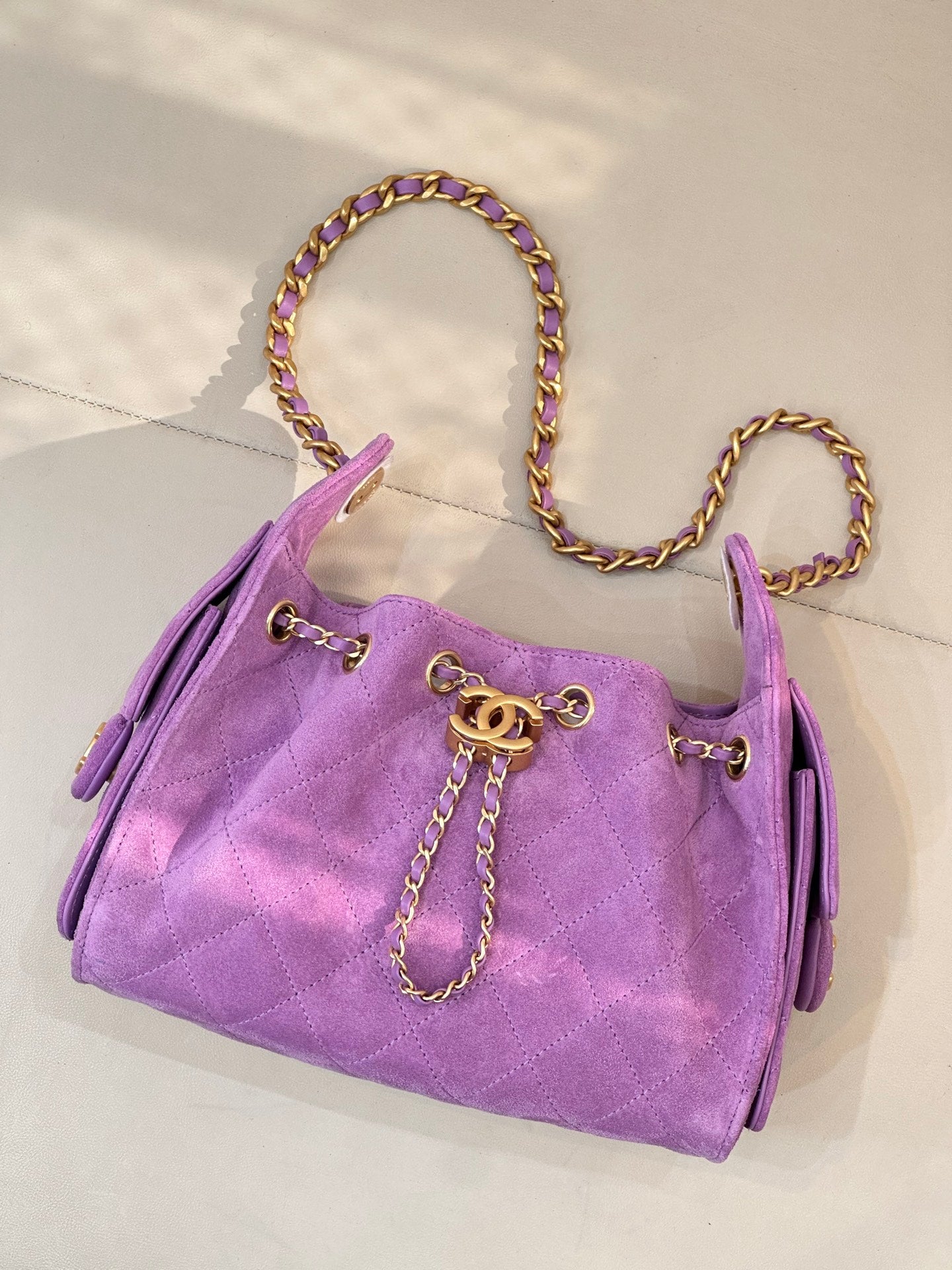 Purple quilted Chanel handbag with chain handles and gold CC charm on front