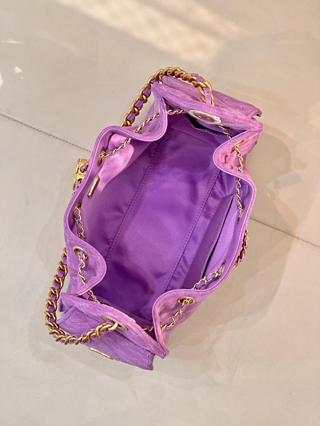 Purple quilted Chanel handbag open at top with gold chains and CC logo hardware