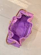 Purple quilted Chanel handbag open at top with gold chains and CC logo hardware