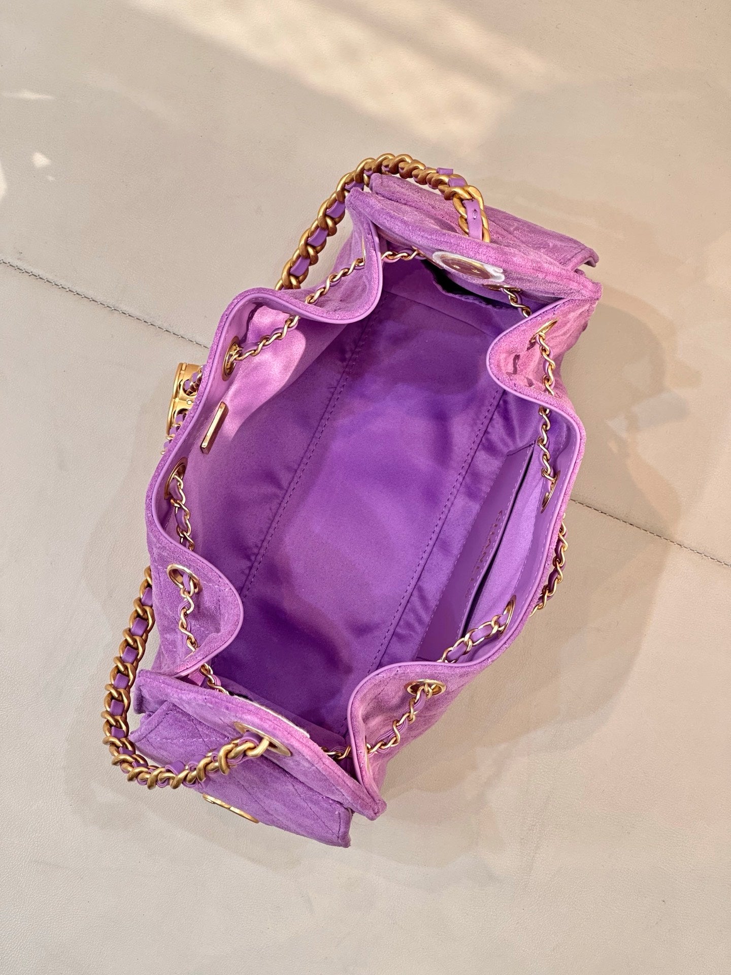 Purple quilted Chanel handbag open at top with gold chains and CC logo hardware
