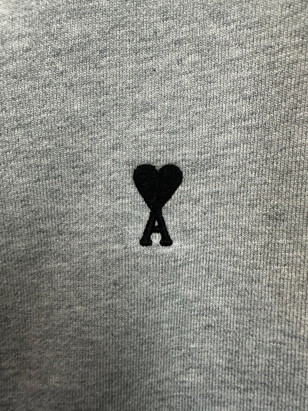 Black heart-shaped logo patch on light gray hoodie fabric