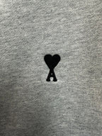 Black heart-shaped logo patch on light gray hoodie fabric
