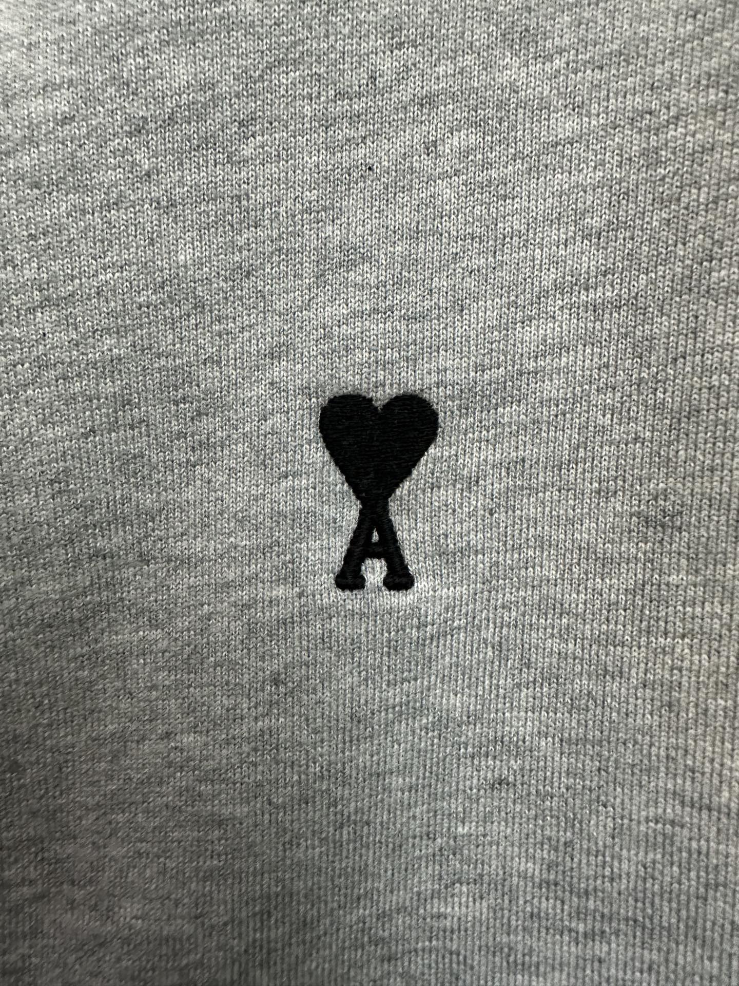 Black heart-shaped logo patch on light gray hoodie fabric