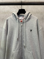 Light gray zip-up hoodie with hood, center zipper, and small black logo on chest