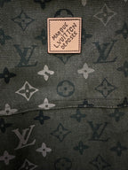 Beige logo patch on olive green monogram fabric.