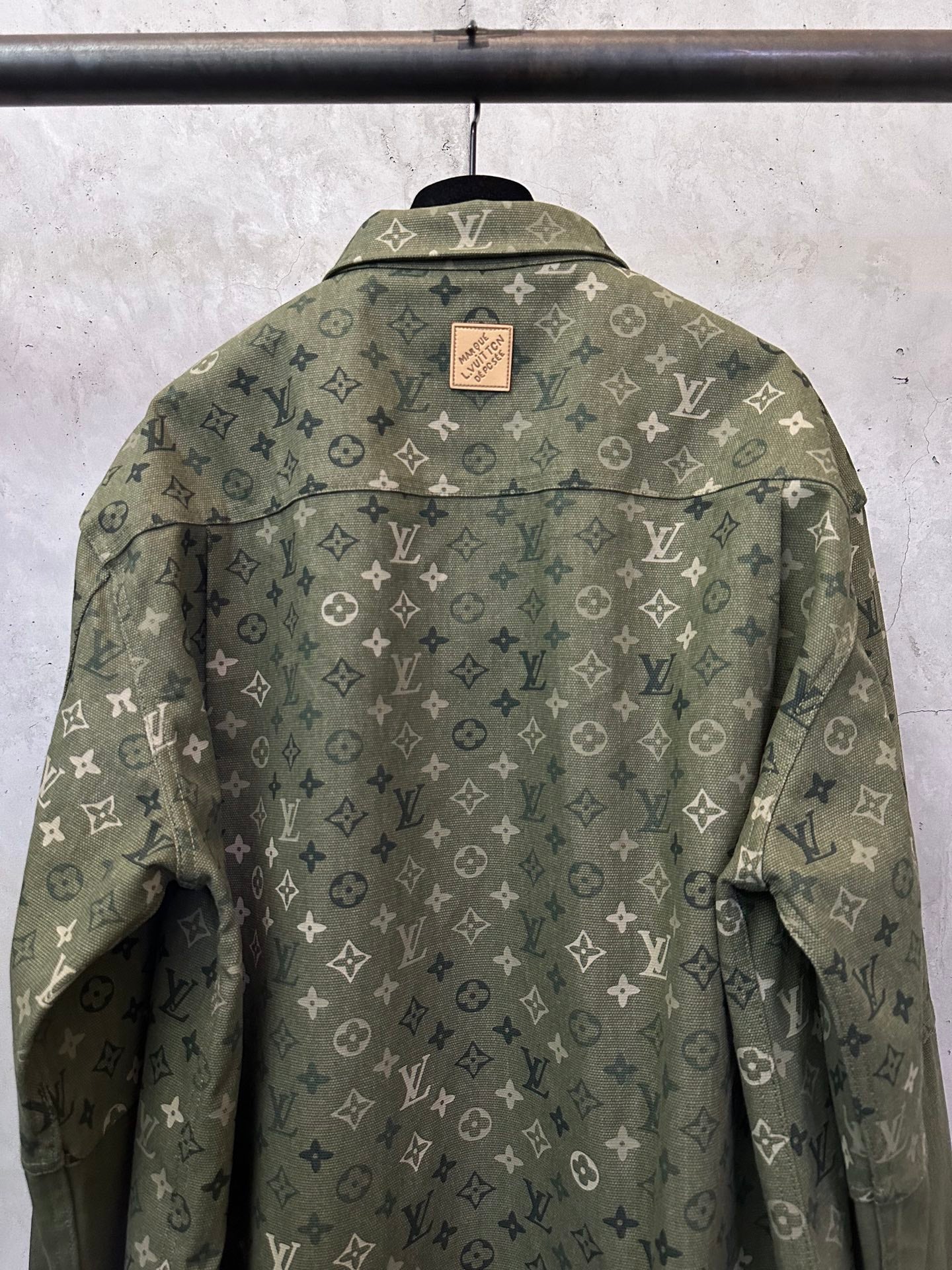 Olive green monogram button-up jacket, back view with brand patch at collar.