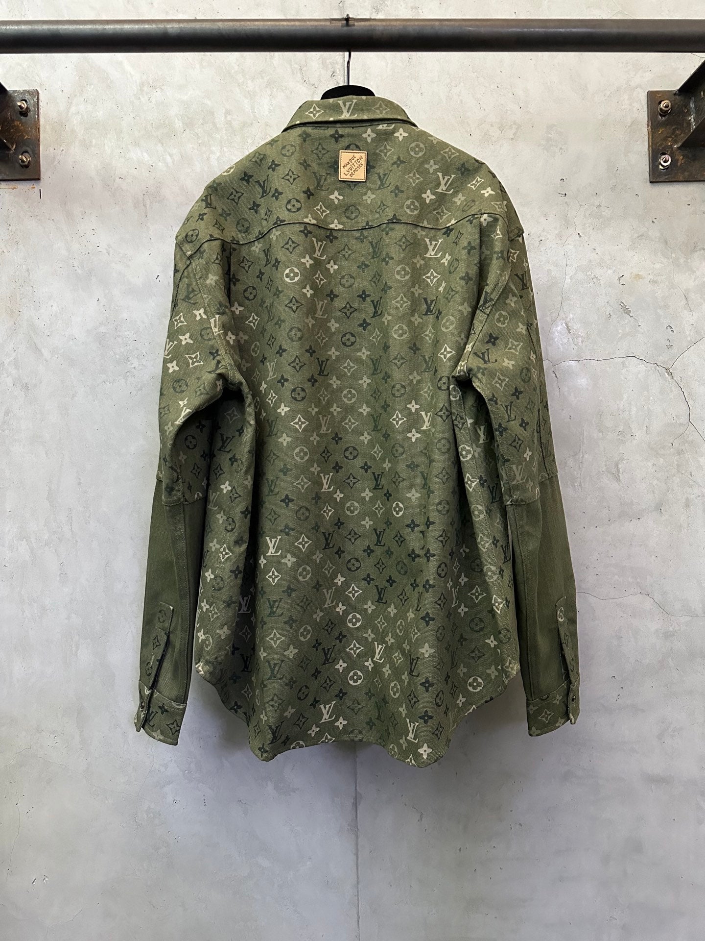 Olive green monogram long-sleeve button-up jacket, back view, flap pockets.