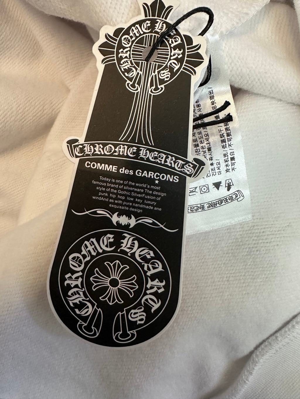 White hoodie with black and white hang tag attached to fabric collar