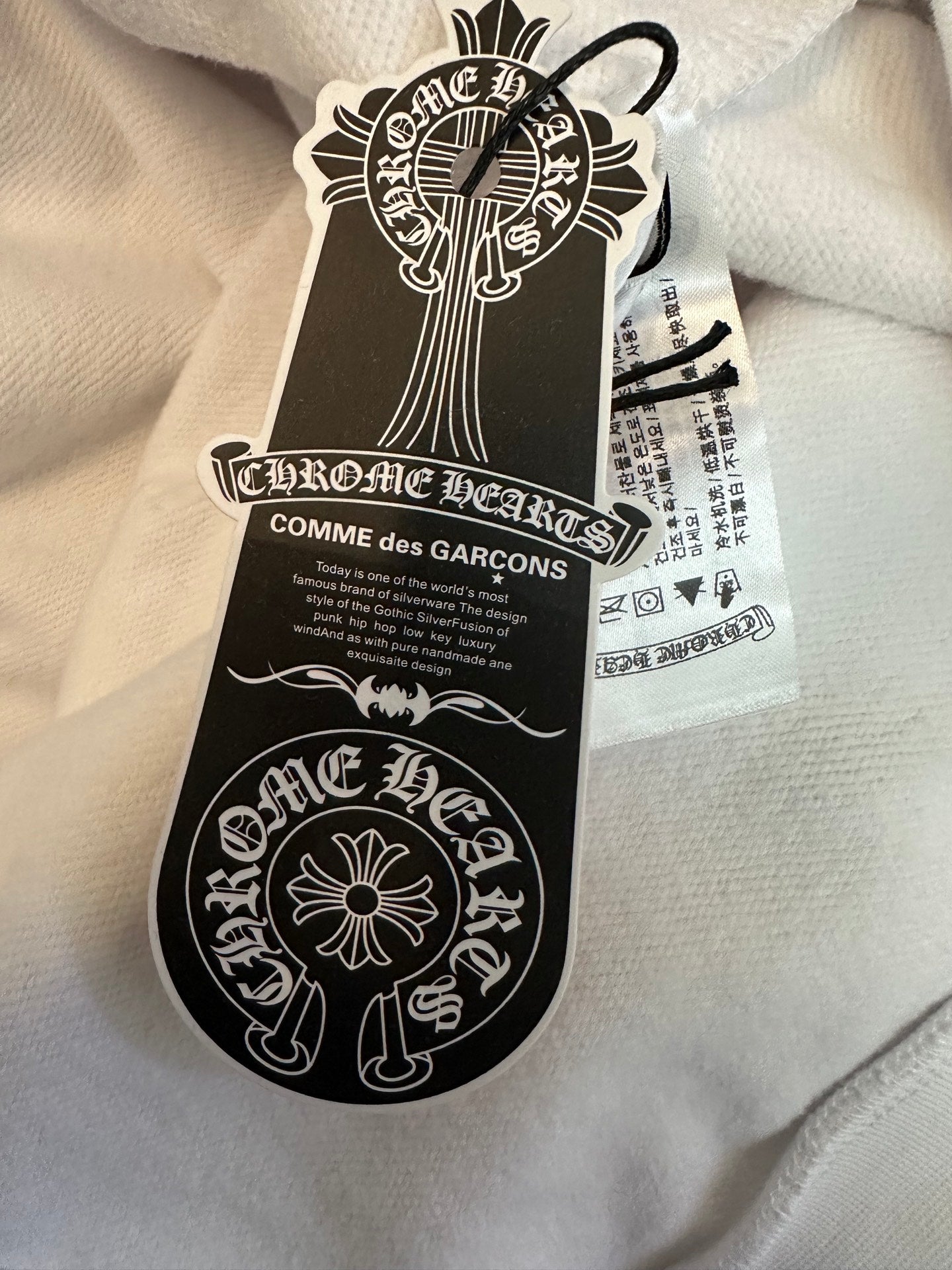 White hoodie with black and white hang tag attached to fabric collar