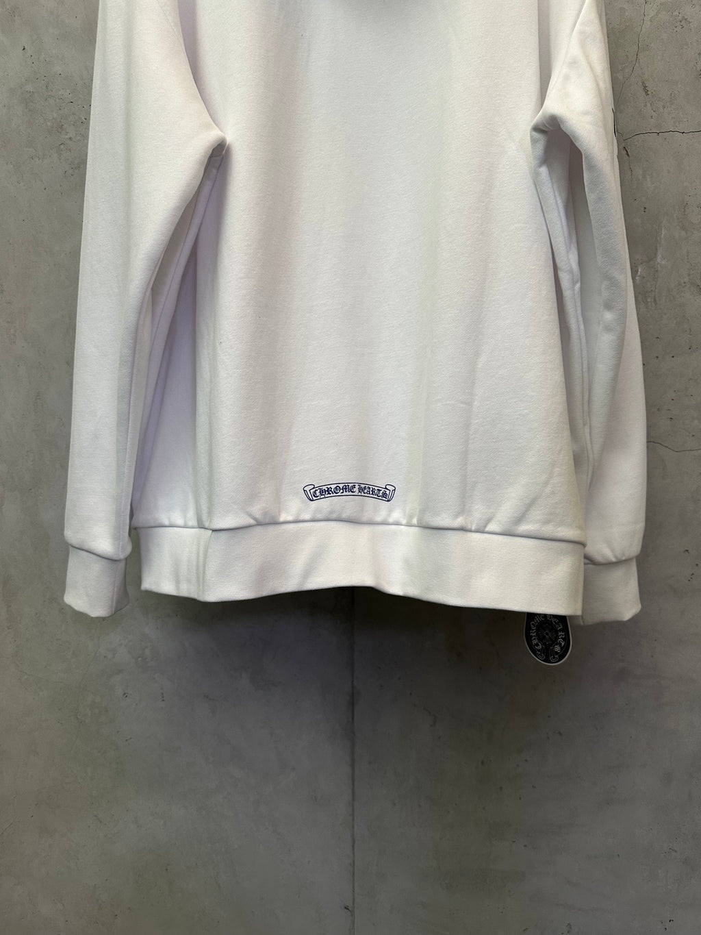 White zip-up hoodie back with small chest logo patch and ribbed hem