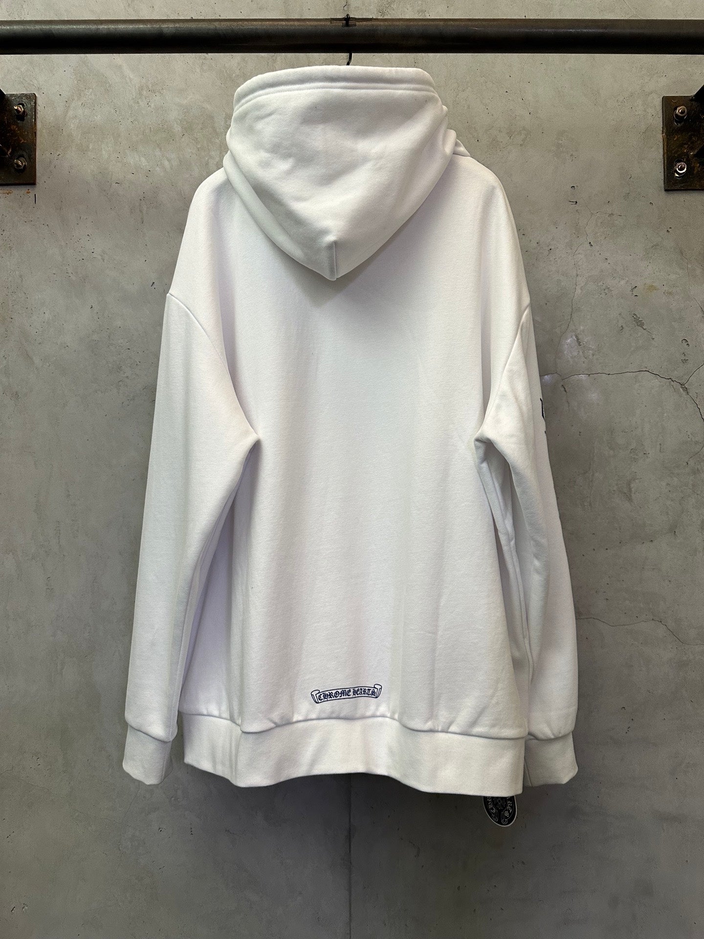 White zip-up hoodie back view with hood and small chest logo patch