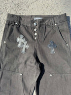 Black cargo pants close-up with front buttons, drawstring cord, and cross embroidery