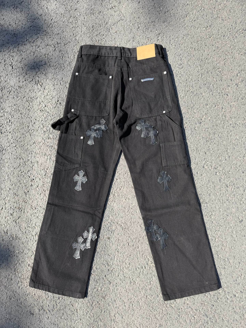 Black cargo pants with cross patches, drawstring tie, and small label at waistband