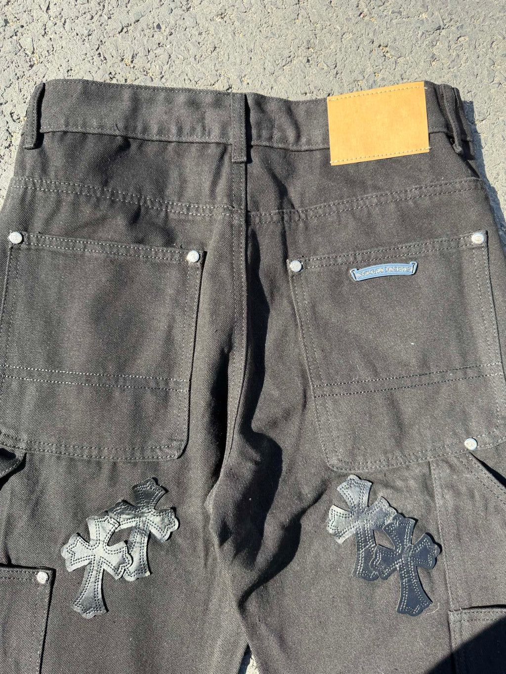Black cargo pants with back pockets and cross patches, yellow label on waistband