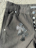 Black cargo pants detail with buttoned side pocket and large cross patch on leg