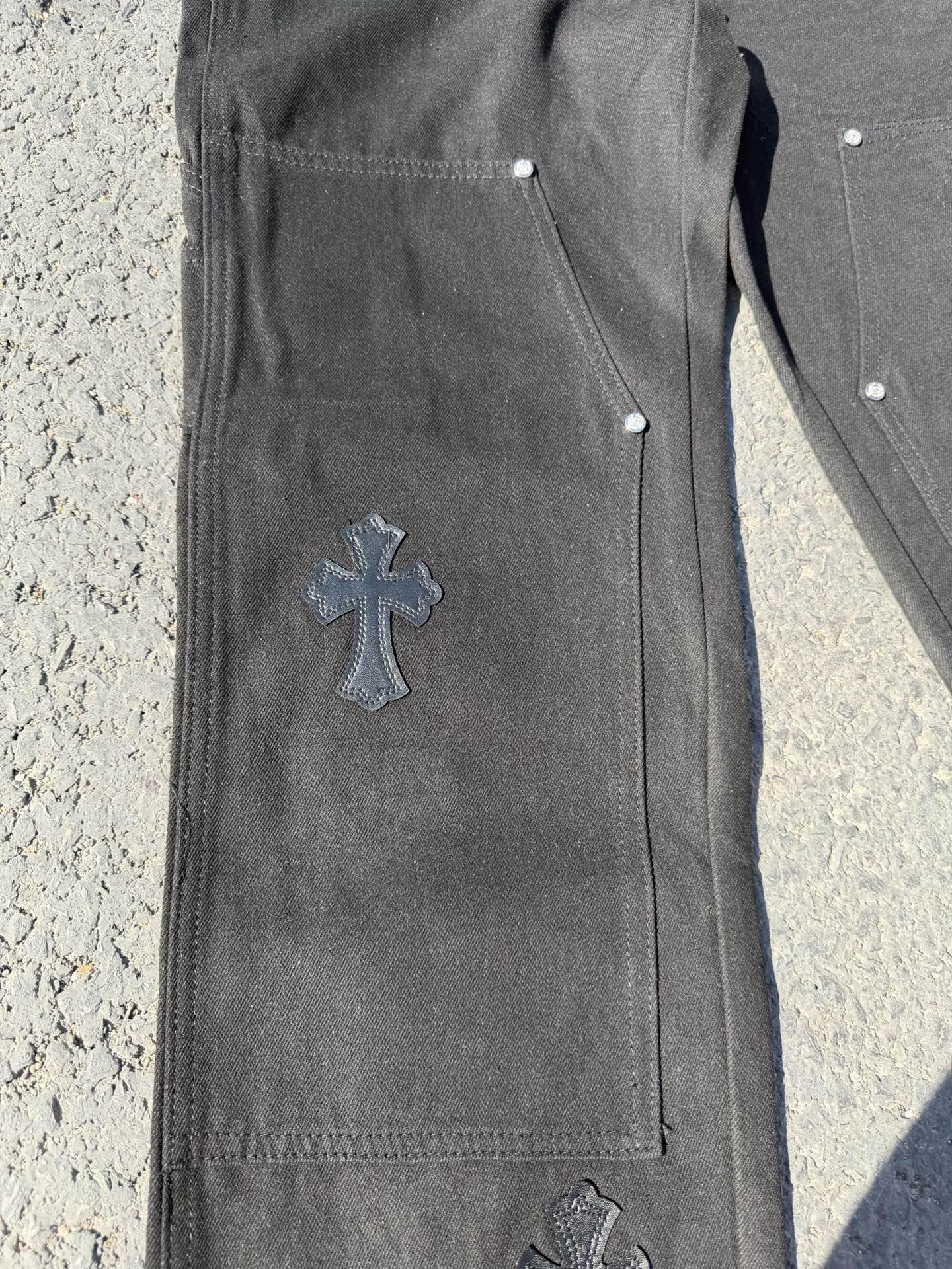 Black cargo pants side view with cross patch on leg and stitched seams
