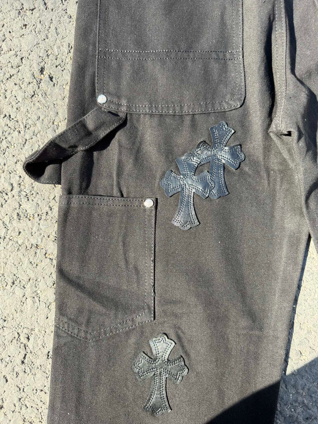 Black cargo pants with thigh pocket, side strap, and cross patch on leg