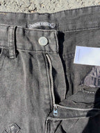 Front detail of dark gray denim pants with metal button and zip fly