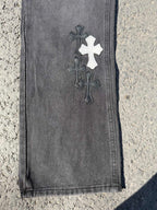 Dark gray jeans pants with dark cross patch near hem