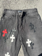 Close-up of dark gray denim pants with front button and cross patches on legs