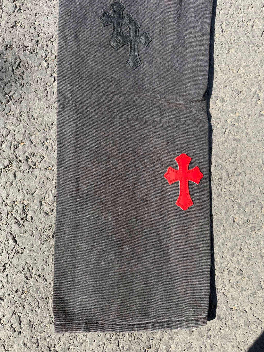 Dark gray jeans pants with red cross patch near hem