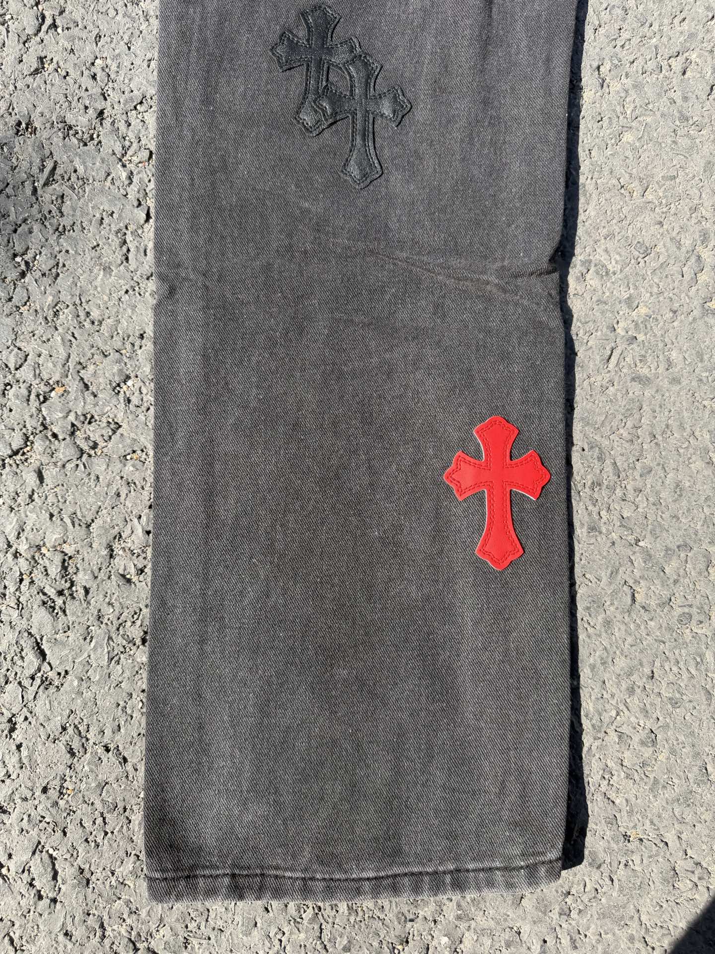 Dark gray jeans pants with red cross patch near hem