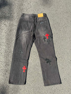 Dark gray denim pants with scattered cross patches in red and white on the front