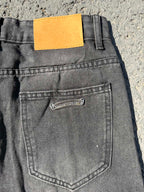 Back pocket close-up on dark gray denim pants with yellow brand patch label