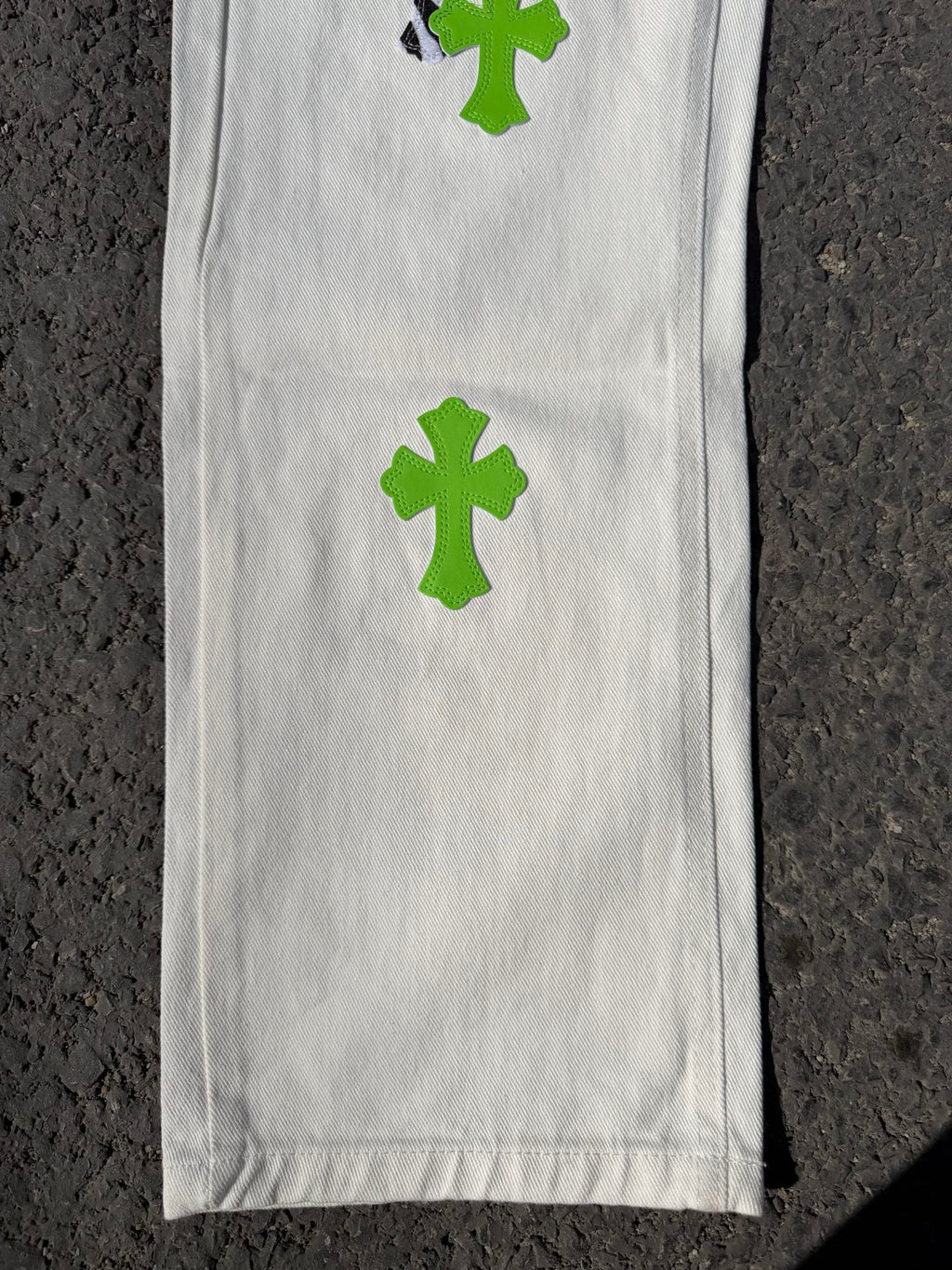 White denim pants leg with green cross patch print and smooth stitched front panel