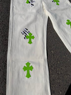 White denim pants close-up with green cross patches across the leg
