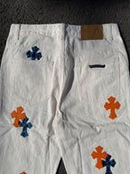 White cross-print pants with side pockets and orange/blue graphics on both legs