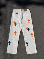 White pants with repeated orange and blue cross graphics, fly front and side pockets
