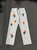 White denim pants with orange and blue cross prints, button front and belt loops