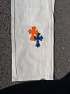 Chrome pants with white fabric and orange and blue cross patches on the leg