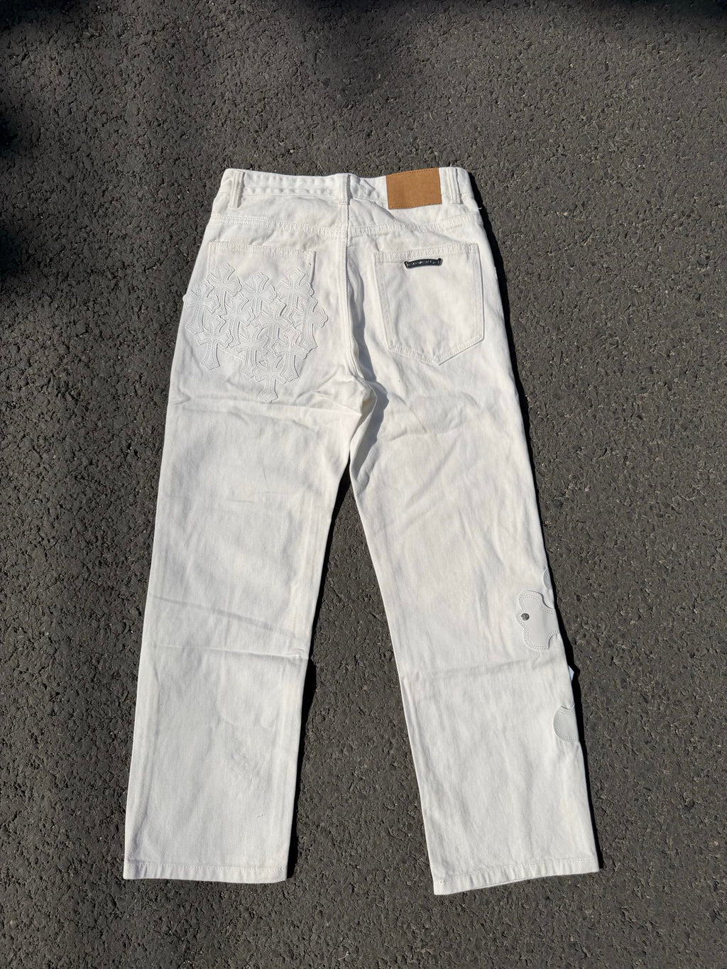 White denim pants with button fly and small chest embroidery on the leg