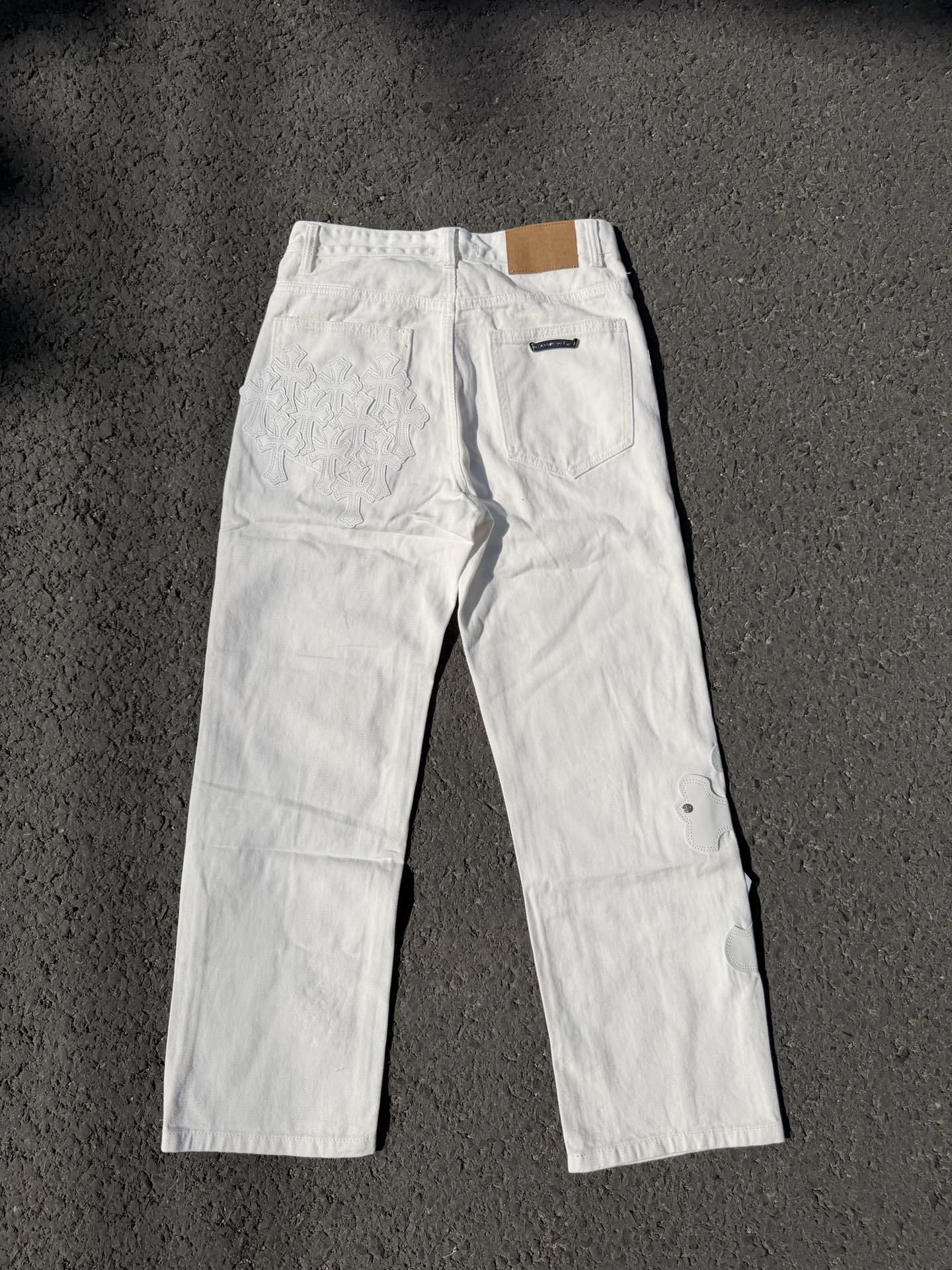 White denim pants with button fly and small chest embroidery on the leg