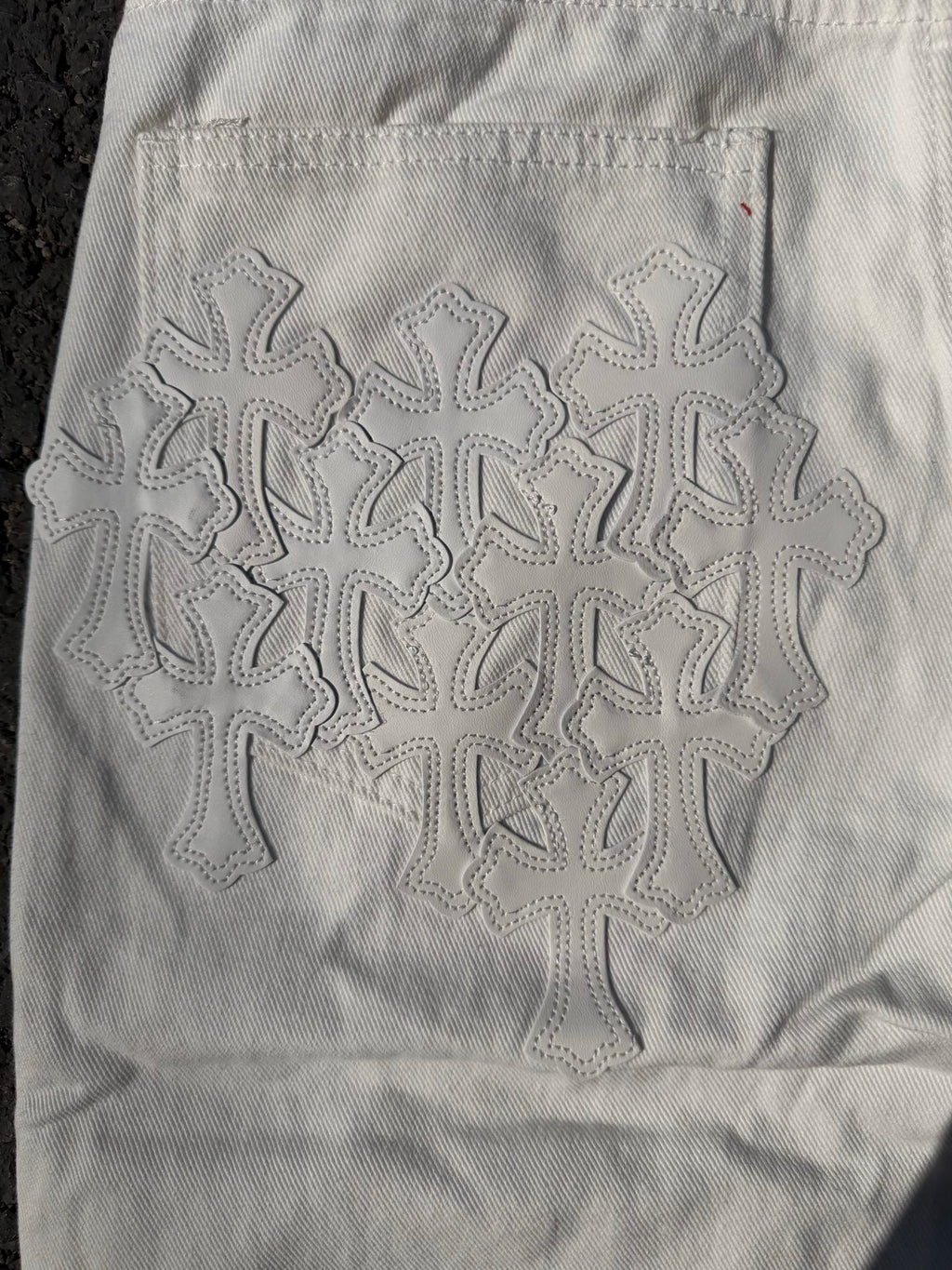 White denim pants with large embroidered floral snowflake pattern on the back