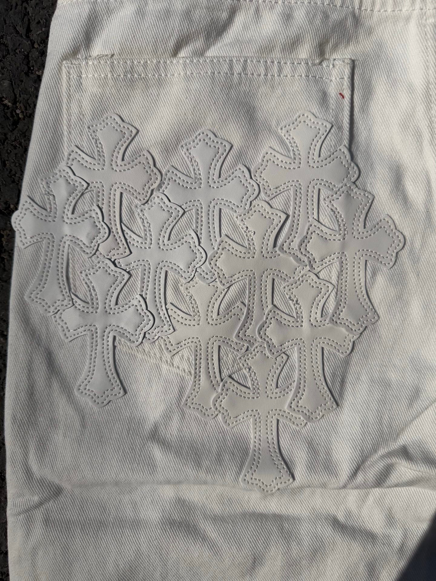 White denim pants with large embroidered floral snowflake pattern on the back
