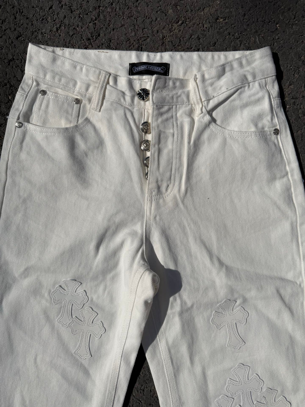 White denim pants with zipper fly, belt loops, and subtle floral appliques