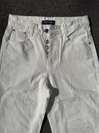 White denim pants with zipper fly, belt loops, and subtle floral appliques