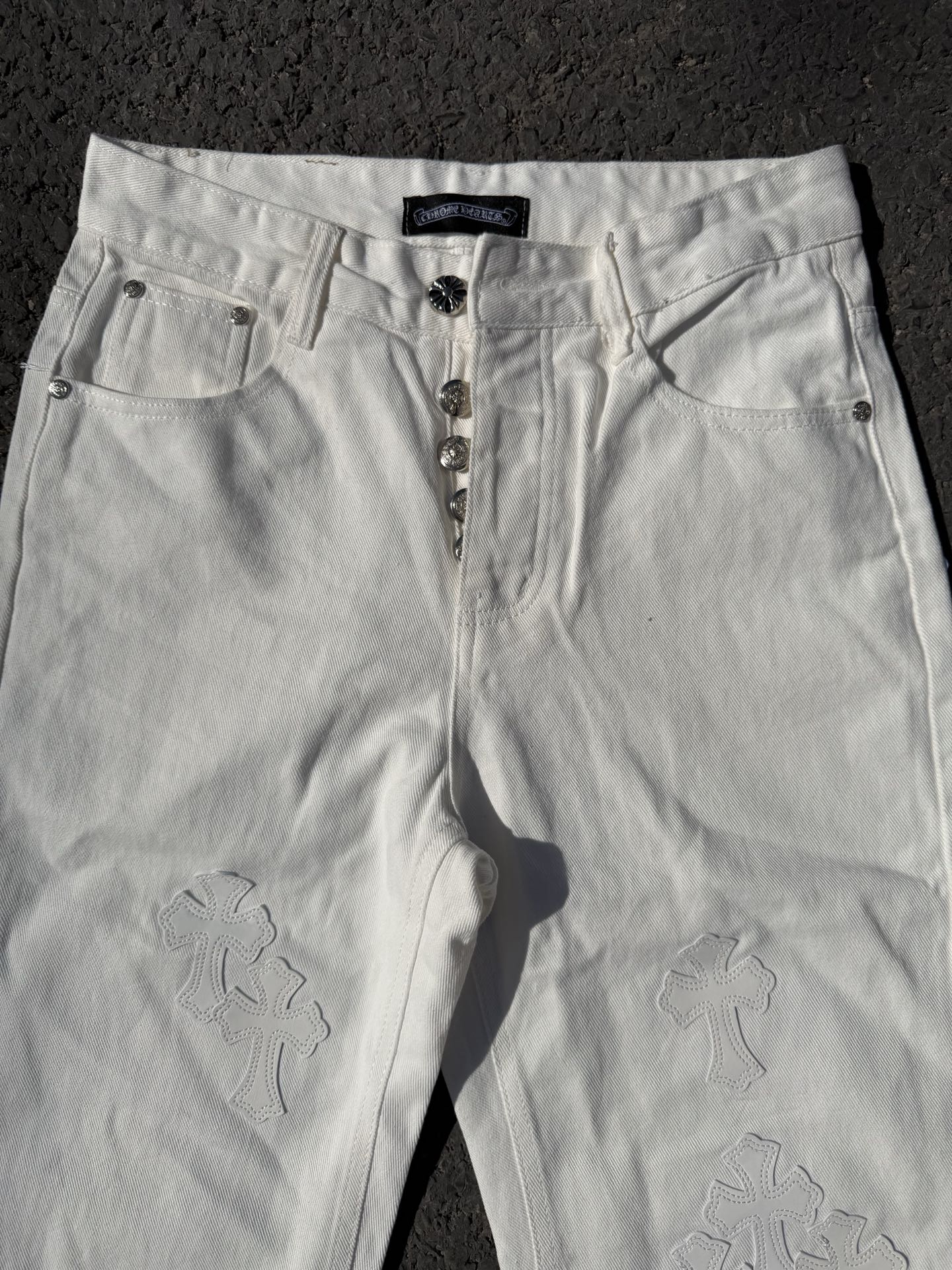 White denim pants with zipper fly, belt loops, and subtle floral appliques