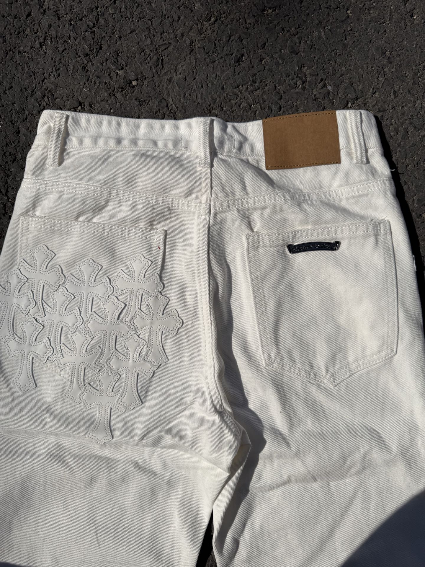 White denim pants with floral stitched panel on the back and front slant pocket